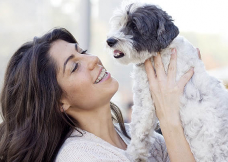 Woman holding a small grey and white dog